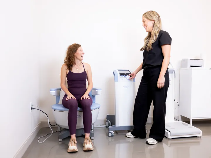 A patient laughing with a clinician during an Emsella session
